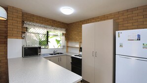 Een kleine keuken met een magnetron, spoelbak, fornuis en koelkast.