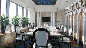 A dining area with a long table set for a meal, surrounded by chairs, with a large chandelier and a television on the wall. - Shenyang Royal Wanxin Hotel (Shenyang)