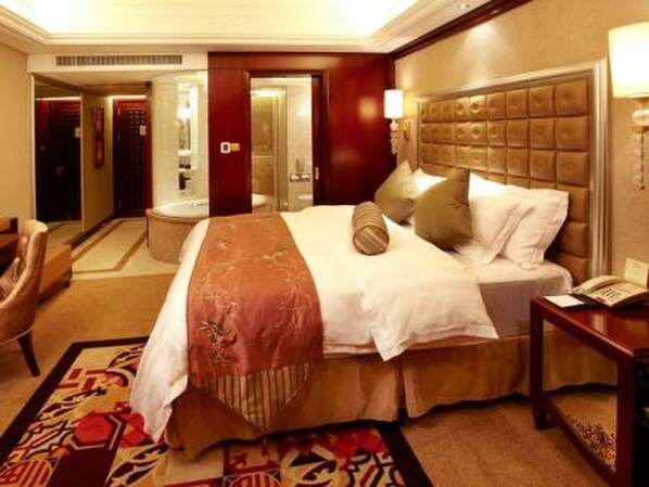 A hotel room with a large bed, a headboard, a bedside table, a chair, and a carpeted floor.