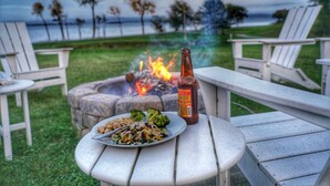 Una mesa de comedor con un plato de comida y una botella, con un hogar y una vista panorámica de fondo.
