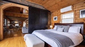 Un dormitorio amplio con una cama grande, paredes de madera y una chimenea acogedora.