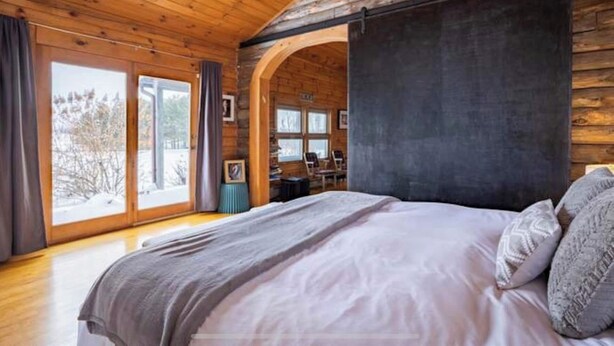 Un dormitorio de caba ña de madera con una cama grande, un escritorio y vistas al exterior.