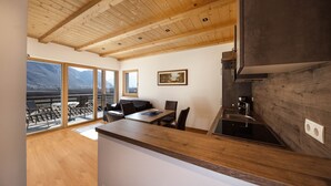 A modern kitchen with wooden ceiling beams, a dining area with a view, and a large window. - Light-Flooded Apartment "2 Weger" with Panoramic Mountain View, Wi-Fi & Balcony (Andrian)
