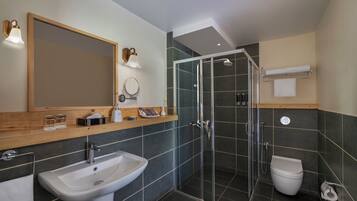 A modern bathroom with a sink, mirror, shower, and toilet.