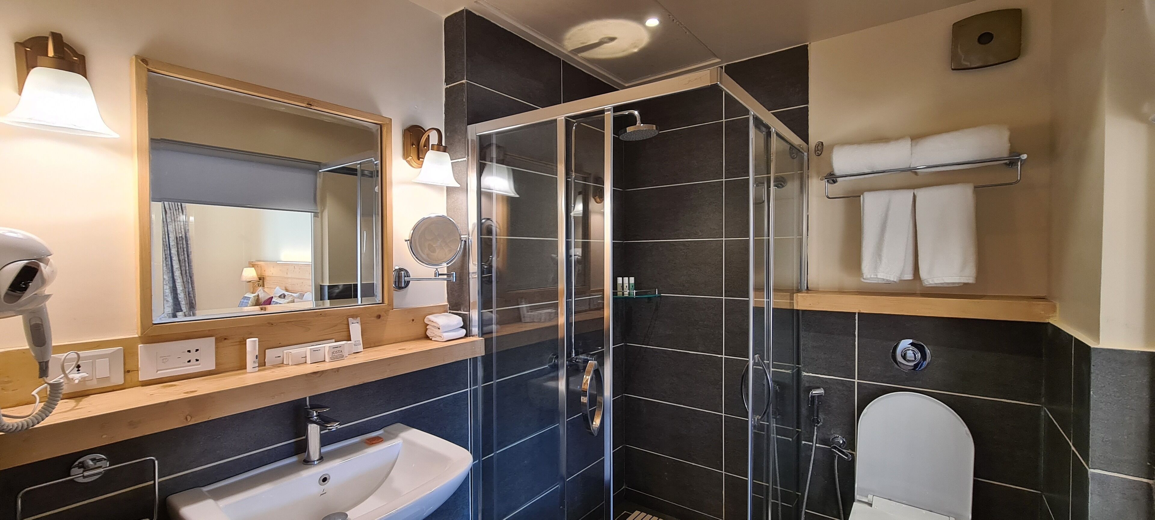 A modern bathroom with a glass-enclosed shower, a large mirror, a sink, and a towel rack.