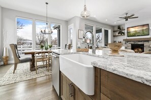 A modern kitchen with a large island, a dining area with a view, and a fireplace.