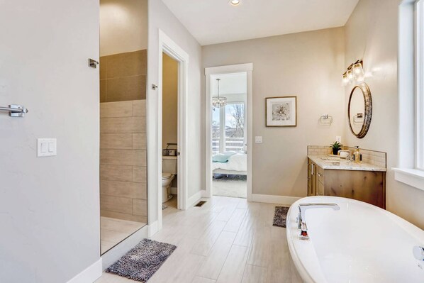 A modern bathroom with a large bathtub, a vanity with a mirror, and a shower area.