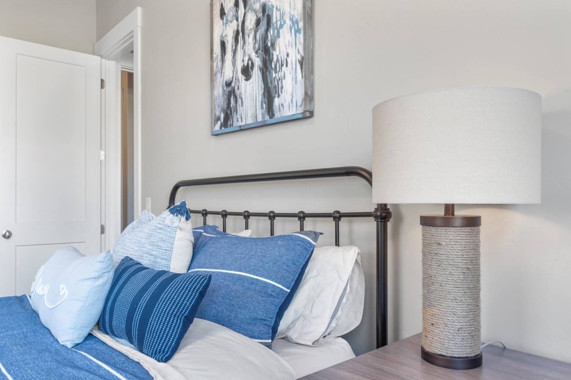 Un dormitorio con cama, almohadas, una lámpara y un cuadro en la pared.