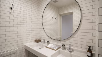 Casa de banho com azulejos brancos, um lavatório branco com espelho e um dispensador de sabonete.