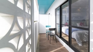 A modern room with a large window, a bed, a chair, and a small table. - Blue Cove Terrace (Miyakojima)
