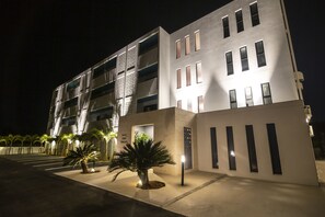 A modern building with a flat facade, multiple balconies, and a well-lit entrance. - Blue Cove Terrace (Miyakojima)