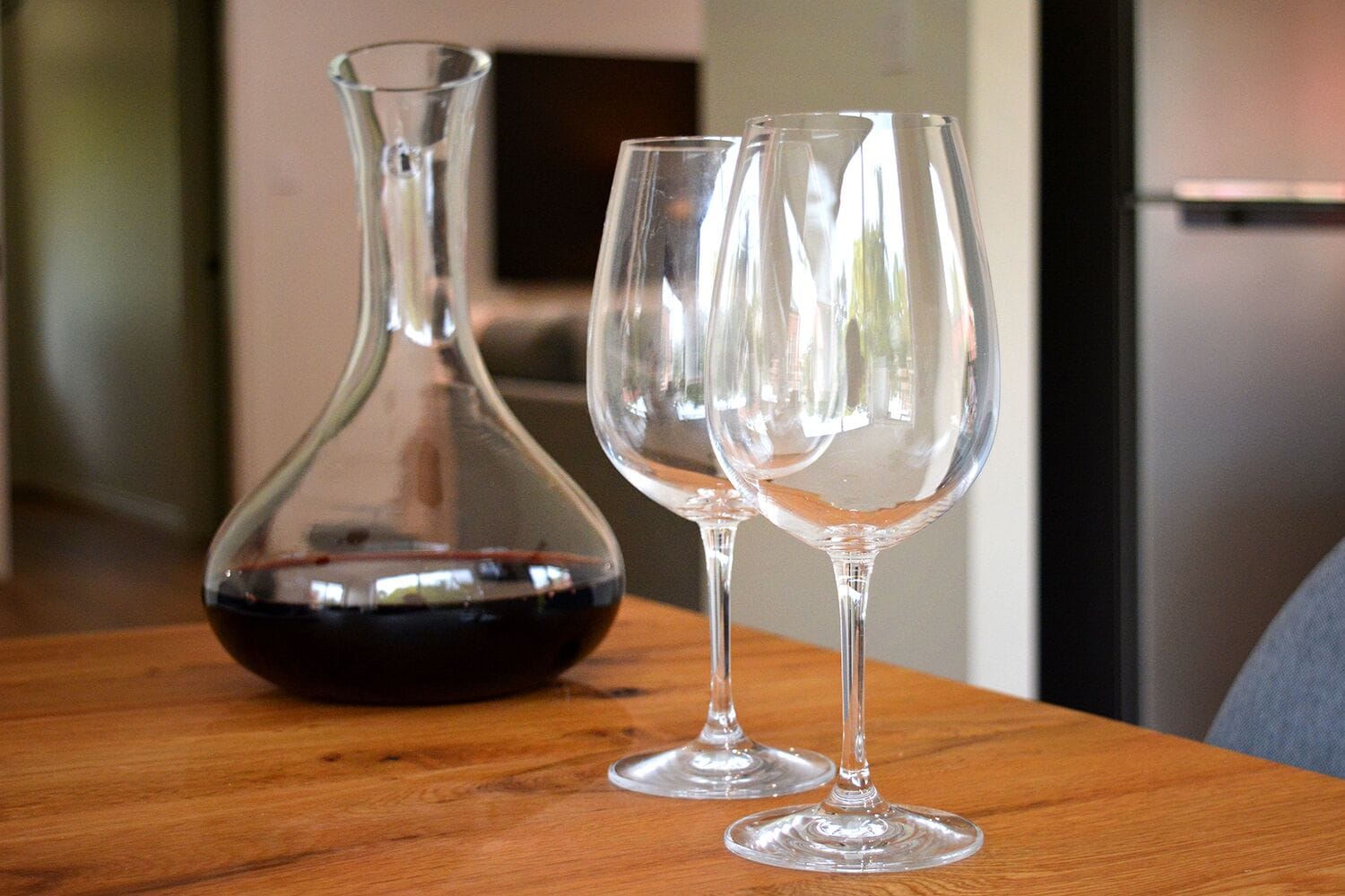 A wooden table with a wine bottle and two wine glasses.