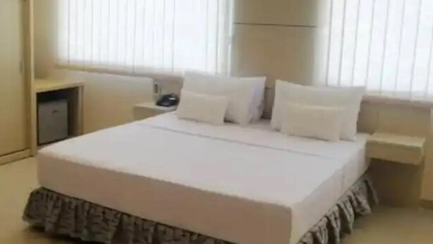 Une chambre à coucher avec un lit, des tables de chevet et une fenêtre avec des stores.