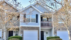 A two-story house with a front porch, a garage, and a driveway. - Charming, Stylish and Cozy 3 Bedroom Townhouse near Athens (Winder)