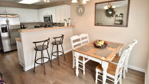 A kitchen with white cabinets, a stainless steel refrigerator, a microwave, and a wooden island with bar stools. - Charming, Stylish and Cozy 3 Bedroom Townhouse near Athens (Winder)