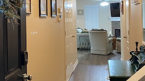 A hallway with a door on the left, a chair and a table on the right, and a fireplace in the background. - Charming, Stylish and Cozy 3 Bedroom Townhouse near Athens (Winder)