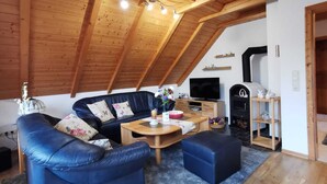 A cozy living room with a black leather sofa, a wooden coffee table, and a television.
