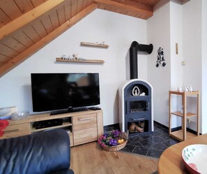 Ein gemütliches Wohnzimmer mit Fernseher, Holzmöbeln, Kamin und dekorativer Regalwand.