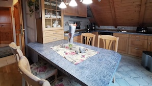 A kitchen with wooden cabinets, a granite countertop, and a dining area with chairs.