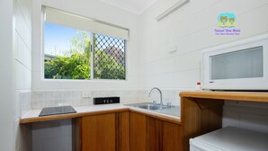 A kitchen with a sink, a countertop, a Hisense refrigerator, and a window with a view of greenery. - Island View Motel (North Ward)