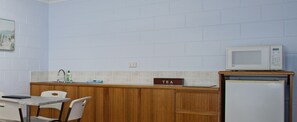 A compact kitchen with a microwave, a sink, and a tea sign on the counter. - Island View Motel (North Ward)