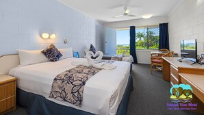 A hotel room with a large bed, a desk, a chair, a TV, and a balcony with a view. - Island View Motel (North Ward)