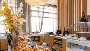 Montaje de bufé con diferentes alimentos, un árbol de Navidad y plantas decorativas.