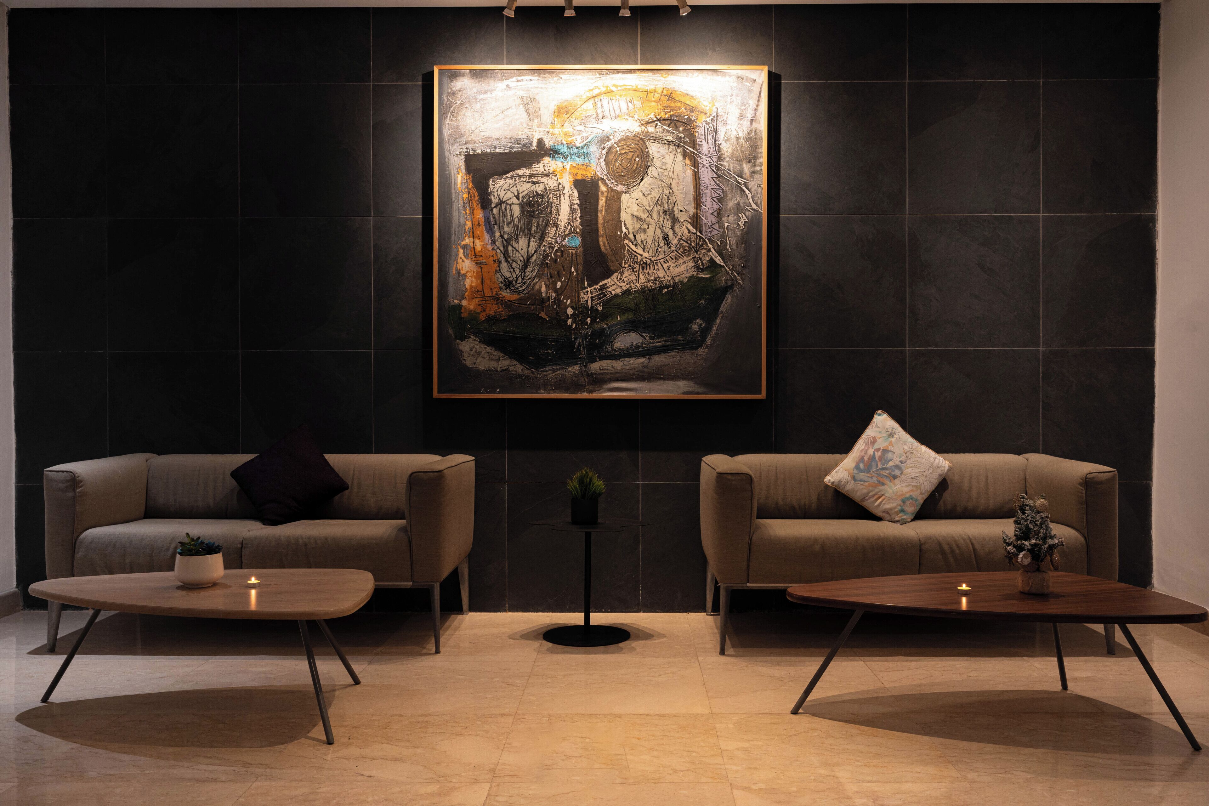 A modern living room with two sofas, a coffee table, and a painting on the wall.