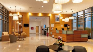 Un moderno vestíbulo de hotel con mostrador de recepción, zona de estar y grandes ventanales.