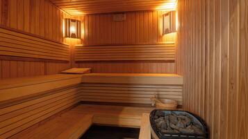 A sauna with wooden benches, a stone basin, and a stone heater labeled 'HARVIA'.