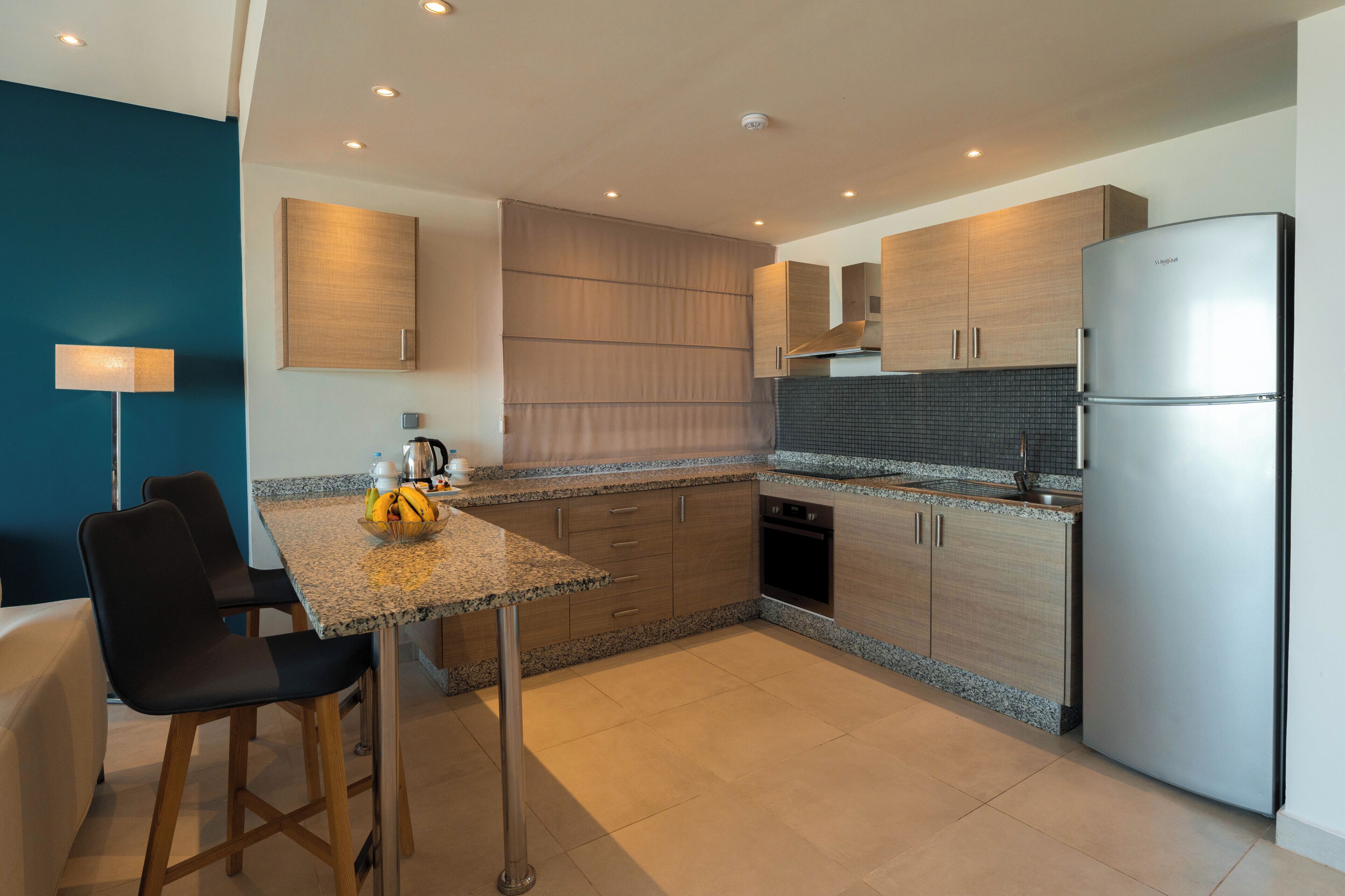 Una cocina moderna con encimeras de granito, electrodomésticos de acero inoxidable y armarios de madera.