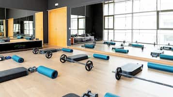 A gym with exercise equipment, large mirrors, and a wooden floor.