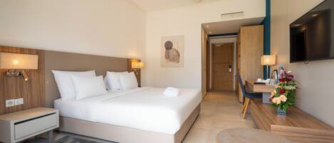 A modern hotel room with a large bed, bedside tables, a desk, and a TV.