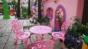 A pink outdoor seating area with chairs and a table, surrounded by plants and a decorative fence. - Victoria Castel (Nantou)