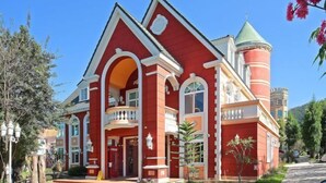 A red building with a tower, arched windows, and a balcony. - Victoria Castel (Nantou)