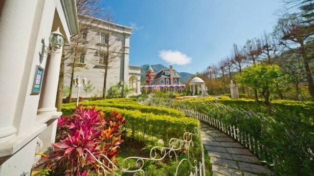 A pathway leading to a building with a traditional architectural style, surrounded by well-maintained gardens and a clear sky. - Victoria Castel (Nantou)