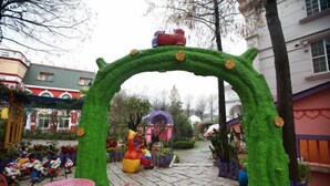 A garden with a green archway, colorful statues, and a pink table. - Victoria Castel (Nantou)