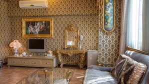 A room with patterned wallpaper, a television, a mirror, a sofa, and a glass coffee table. - Victoria Castel (Nantou)