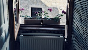 A window view of a stone building with a tiled roof, a radiator, and potted plants with flowers. - La Dolce Vita a few steps from everything Beaune has to offer (Beaune)