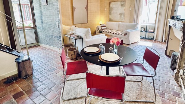 A dining area with a round table, red chairs, and a hanging light fixture. - La Dolce Vita a few steps from everything Beaune has to offer (Beaune)