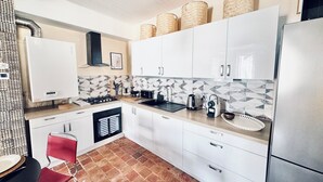 A modern kitchen with white cabinets, a gas stove, a sink, and a tiled backsplash. - La Dolce Vita a few steps from everything Beaune has to offer (Beaune)