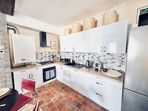 Een moderne keuken met witte kasten, een gasfornuis, een spoelbak en een betegelde spatwand.