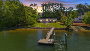 A lakeside property with a dock, a house, and surrounding greenery.