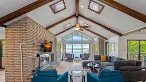 A spacious living area with a fireplace, comfortable seating, and large windows offering a view of the outdoors.