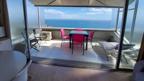 Varanda com mesa e cadeiras, com vista para o oceano.