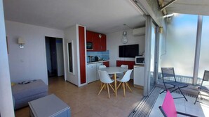 Um apartamento moderno com cozinha, área de refeições e varanda com espaço para sentar ao ar livre.