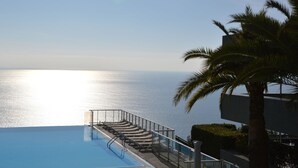 Piscina com vista para o mar, uma palmeira e um edifício.