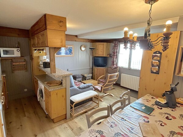 A cozy, rustic kitchen with wooden cabinets, a microwave, and a dining area with a table and chairs.