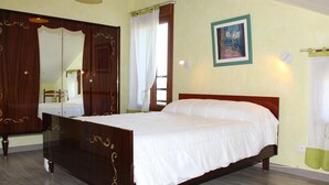 Un dormitorio con una cama de madera, un espejo grande, un cuadro y una lámpara amarilla.
