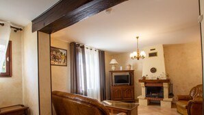 Una sala de estar con chimenea, sofás de cuero, televisor y candelabro.